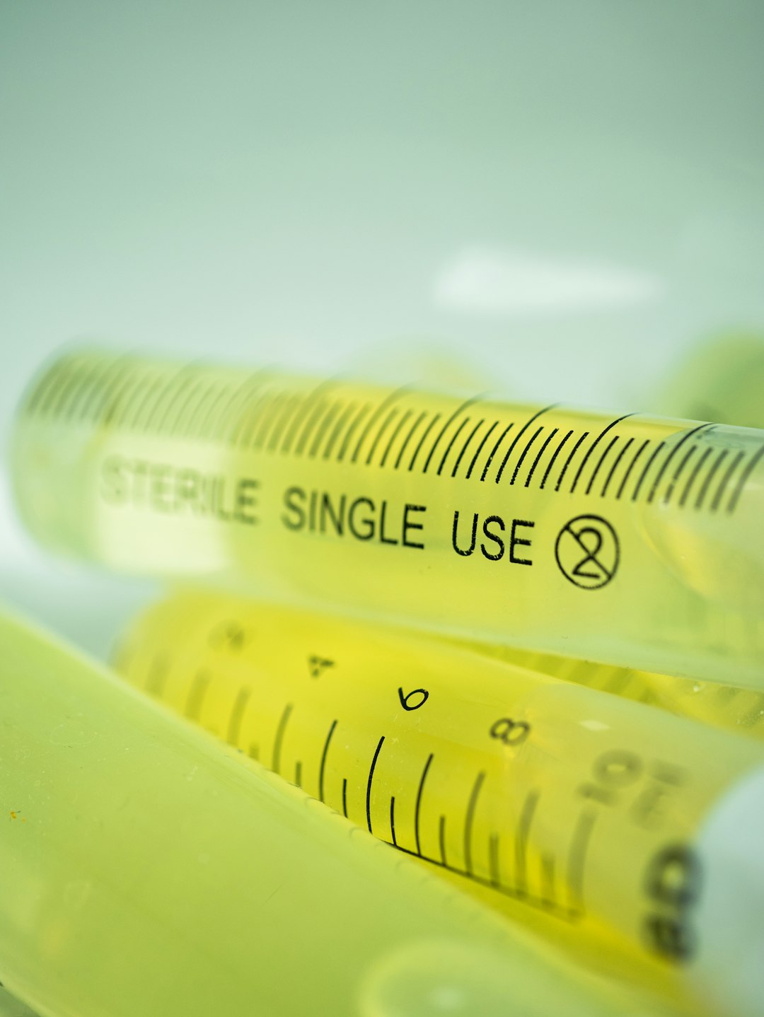Syringes filled with yellow liquid are shown.
