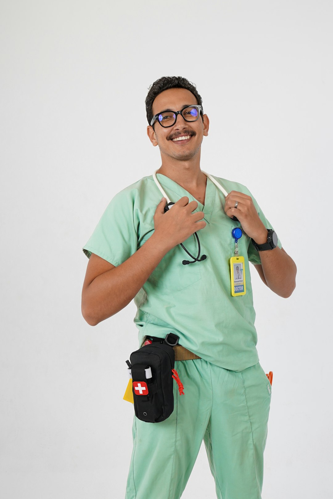 A man in a green scrub suit holding a toothbrush