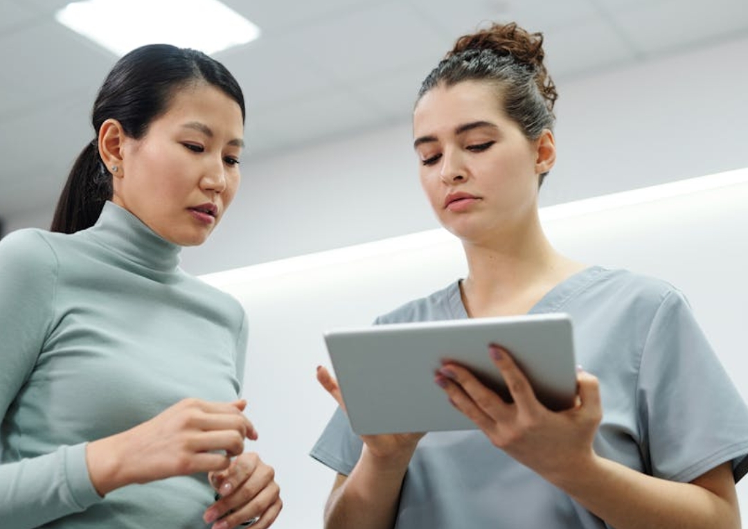 Caregiver assists two elderly women knitting