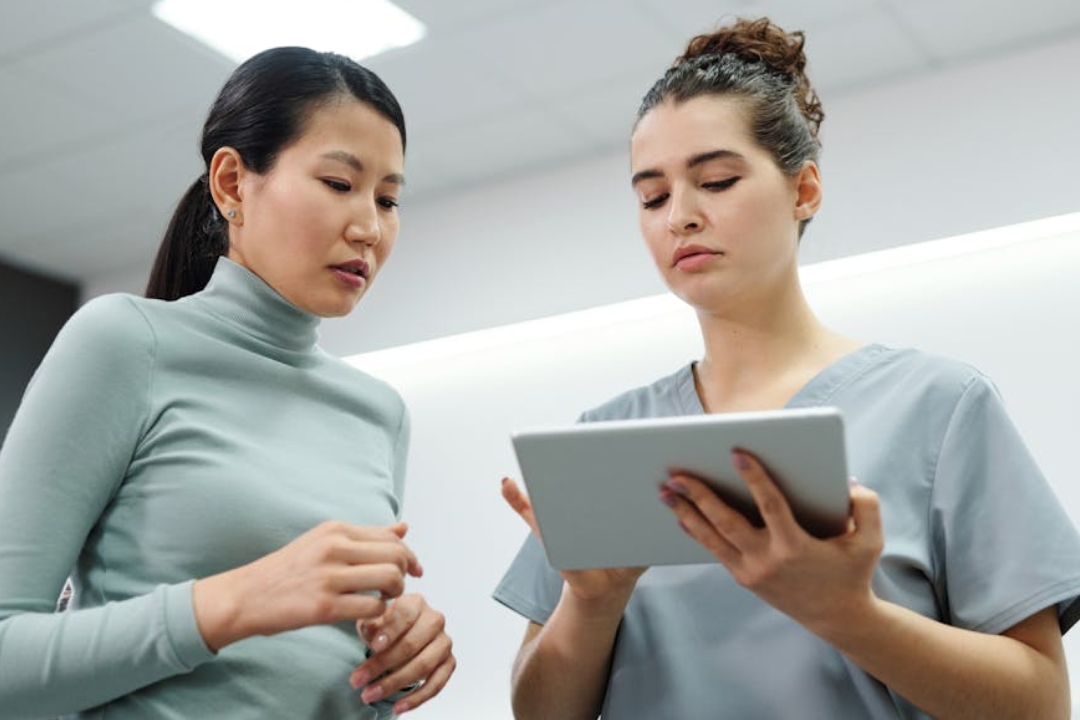 Woman pets a bulldog on a couch with dog toys.