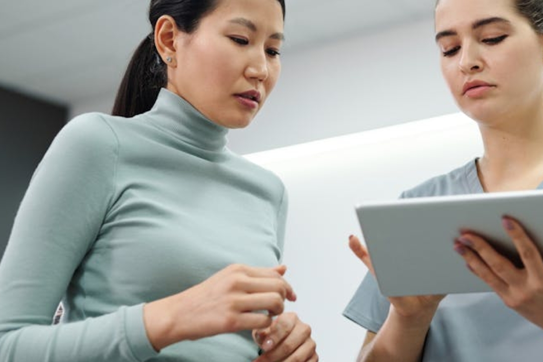 Woman pets a bulldog on a couch with dog toys.